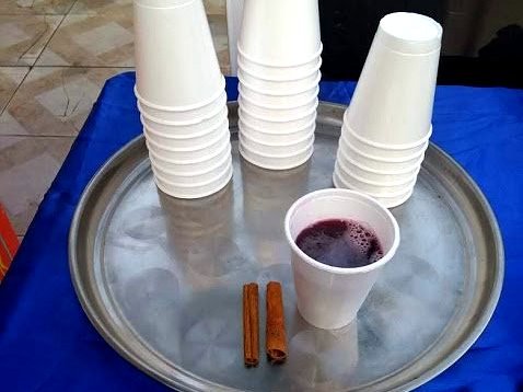 Quentão servido em copo com canela, em bandeja de festa junina